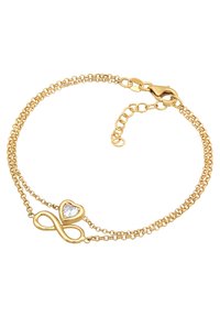 Guldbelagt armband med dubbel kedja, med en oändlighetssymbol och ett hjärta med en klar ädelsten i mitten. Låsning ingår.