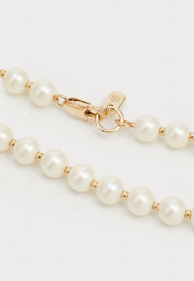 Chaîne de couleur or ornée de perles blanches rondes, entrecoupées de petites perles en métal. Fermeture sécurisée avec un fermoir mousqueton.