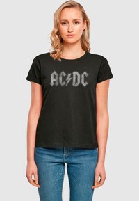 Schwarzes Baumwoll-T-Shirt mit dem AC/DC-Logo in Grau. Standardpassform mit kurzen Ärmeln und einem runden Ausschnitt. Lässiger Stil für den Alltag.
