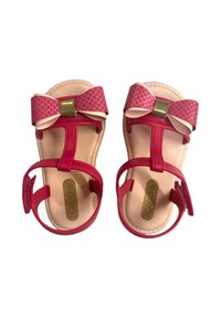 Infradito rossi con un fiocco rosa testurizzato e dettagli dorati, dotati di cinturini alla caviglia regolabili e una soletta beige.