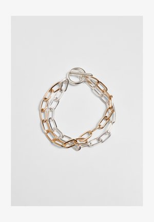 Metallist kett, millel on kuldse ja hõbedase segatud viimistlus. Lingid on piklikud ja ovaalsed, lukustuseks on togglekinnitus.