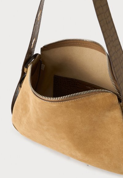 Sac à bandoulière en daim marron clair avec un zip ouvert, montrant un intérieur beige et une sangle texturée marron foncé ainsi qu'une pochette intérieure.