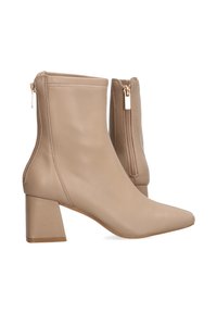 Botines beige de cuero suave, con puntera puntiaguda y tacón cuadrado, que cuentan con cremalleras en los lados exteriores para el cierre.