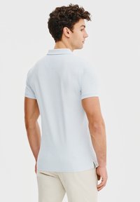 Jasnoniebieska koszulka polo wykonana z bawełny, z klasycznym kołnierzykiem, krótkim rękawem i bocznymi rozcięciami dla większego komfortu.