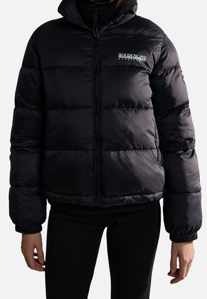 Personne portant une veste matelassée noire Napapijri avec une fermeture éclair à l'avant, des poignets élastiques, et un logo sur la poitrine et la manche gauche.