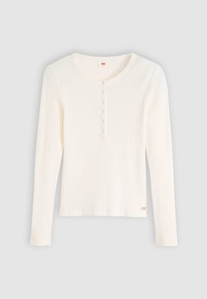 Top de manga larga acanalado en blanco roto con cuello redondeado. Cuenta con una tapeta de botones y una etiqueta del logo en la parte inferior izquierda. Textura suave.