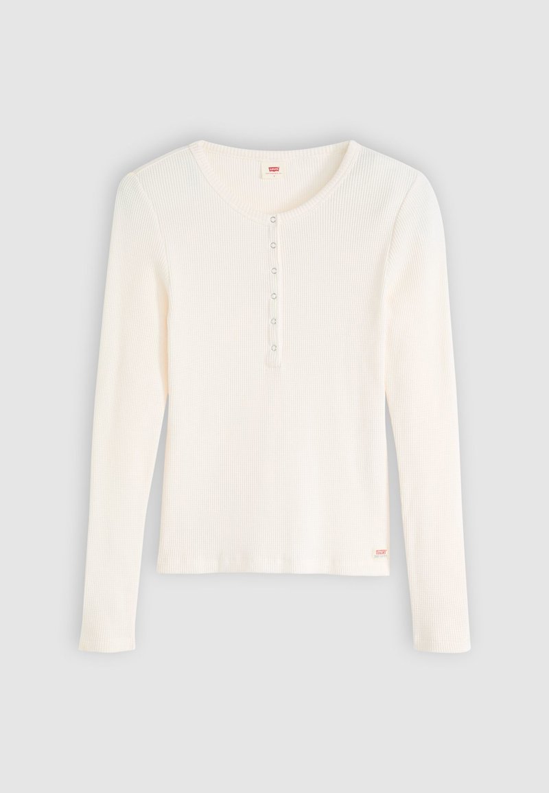 Top de manga larga acanalado en blanco roto con cuello redondeado. Cuenta con una tapeta de botones y una etiqueta del logo en la parte inferior izquierda. Textura suave.