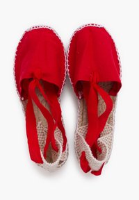 Zapatos de tela rojos con suelas trenzadas blancas, con una parte superior suave, cintas atadas en la parte delantera y un borde trenzado a lo largo de los bordes.