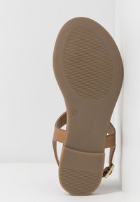 Braune Sandale mit flacher Gummisohle, ausgestattet mit kreuzweise angeordneten, durchlöcherten Riemen und einer kleinen goldfarbenen Schnalle. Größe gekennzeichnet als 37.