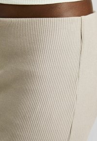 Beige ribbad kjol med en mjuk textur, subtila vertikala linjer och en sidoseamsdetalj för en figurnära look.