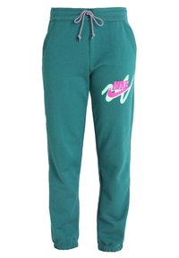 Teal joggerbyxor med elastiska avslut och dragsko i midjan. Har en rosa och mintgrön Nike-logotyp på vänster ben. Material i bomullsblandning.