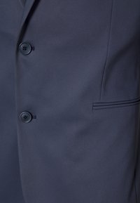 Blazer blu navy in tessuto liscio, caratterizzato da due bottoni, un dettaglio tasca discreto e una linea slanciata e strutturata. Vestibilità regolare senza decorazioni.