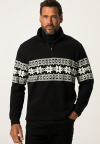 Suéter negro con cuello con cremallera que presenta un patrón de copos de nieve blancos en el pecho. La tela tiene un acabado texturizado y mangas largas.