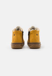 Botas de tobillo de ante amarillo con cremalleras laterales, forro acolchado y suelas de goma texturizadas con un patrón de diamante. Tacón reforzado y detalle de logo.