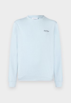 Svetlo modra majica z okroglim izrezom, izdelana iz mehke tkanine, z dolgimi rokavi in malim črnim logotipom na zgornjem levem delu prsnega koša.