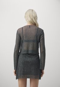 Černý, průhledný dvoudílný outfit s dlouhými rukávy a krátkou sukní. Texturovaná tkanina s metalickým leskem, obsahující zkrácený, boxový design topu.
