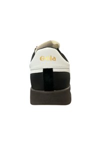 Black and white leather sneaker with a beige collar, gold "Gola" logo, and black suede accent on the heel. Rubber sole for grip.
