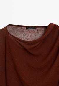 Pull léger marron en maille avec un col rond et une étiquette noire "Massimo Dutti" cousue à l'intérieur du col.
