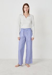 Haut à manches longues côtelé gris clair avec un collier associé à un pantalon de pyjama ample à rayures bleues et blanches. Tissu doux, coupe décontractée.