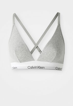 Grå trekantet bralette med kryssede justerbare stropper, en hvit underband med svart "Calvin Klein"-logo, og glatt tekstur.