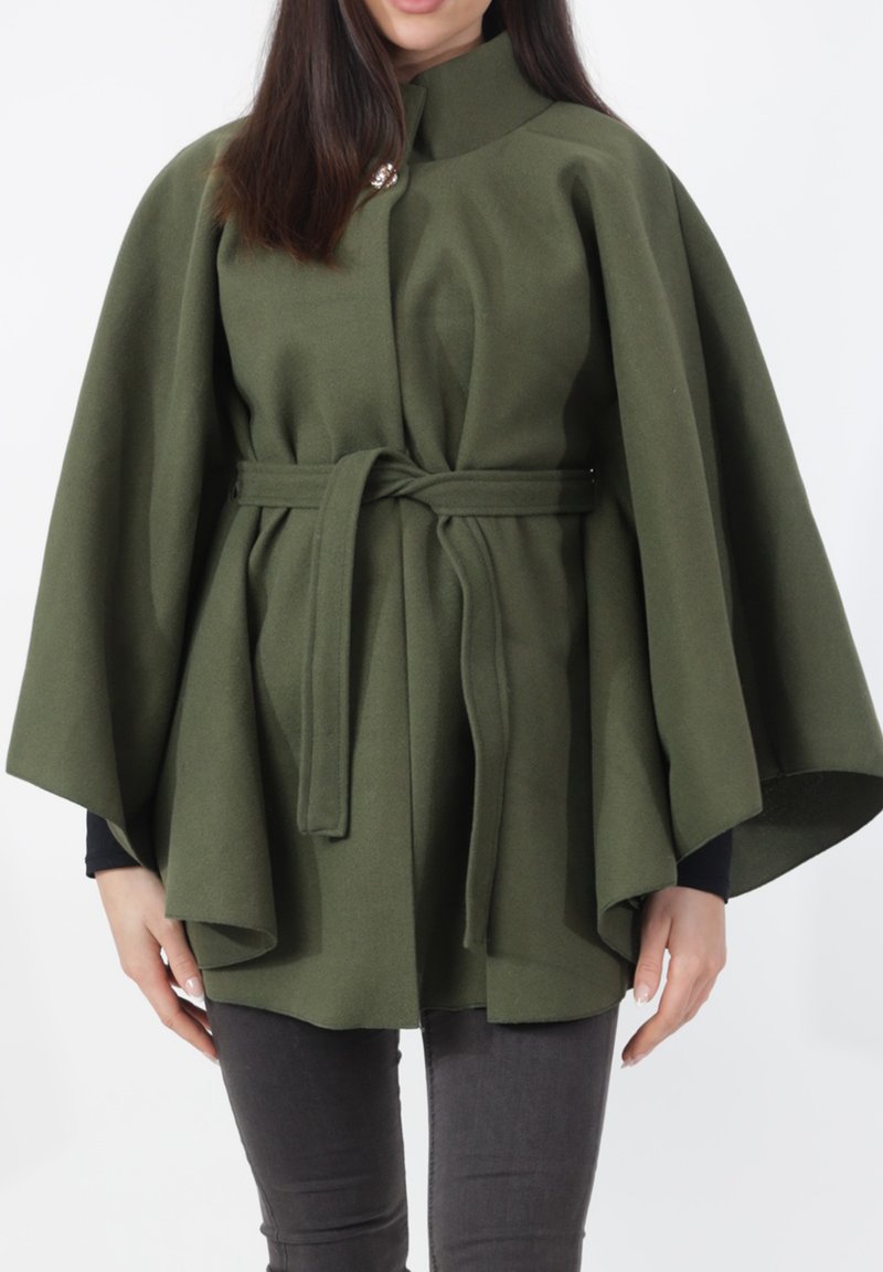 Olijfgroene wollen cape met een hoge kraag, vooraan sluiting met een knoop en een ceintuur in de taille. Heeft brede mouwen en een getextureerde afwerking.
