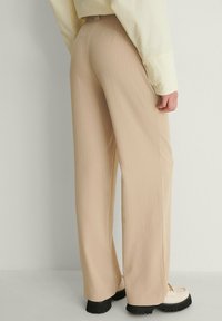 Beige, randiga byxor med breda ben, tillverkade av ett mjukt material, med midjehög design och en elegant, skräddarsydd look.