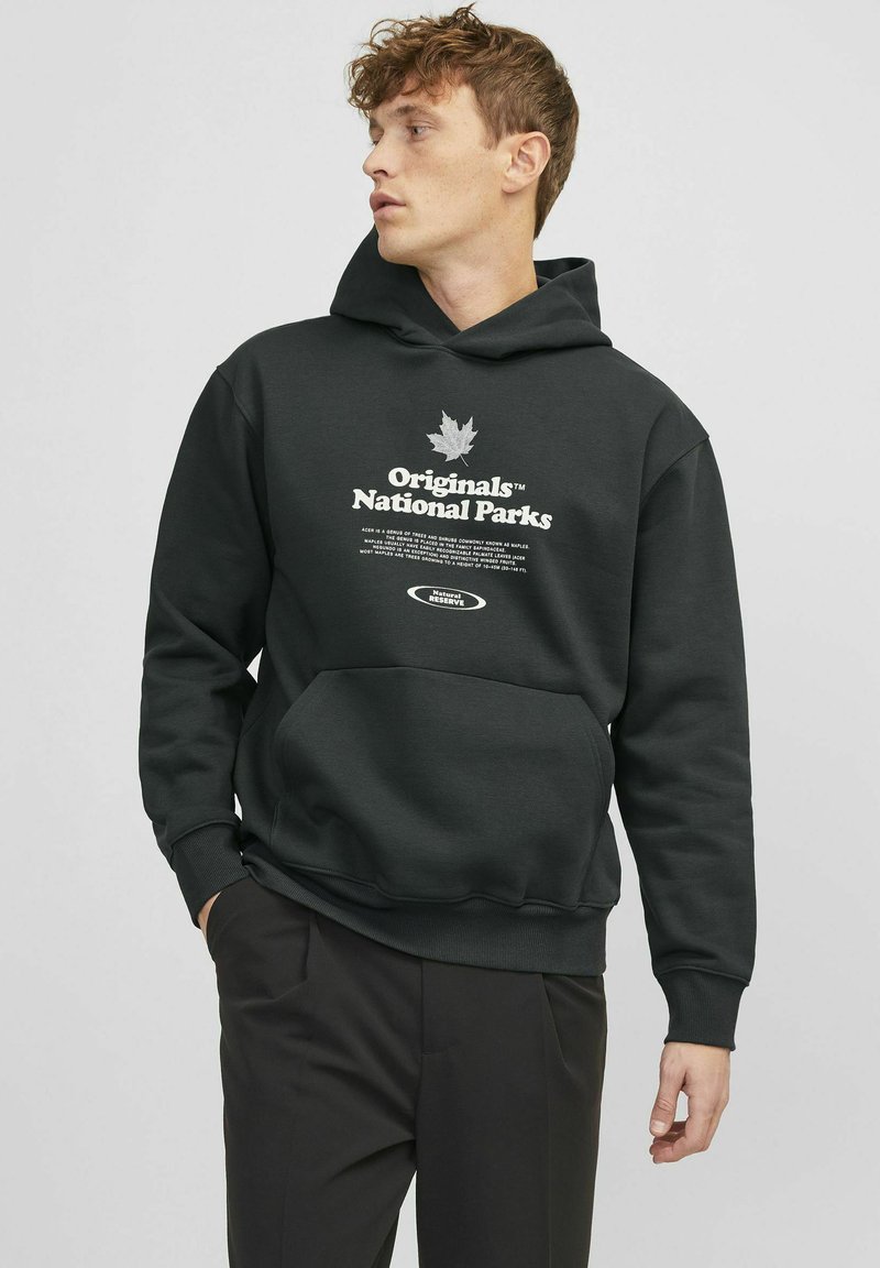 Sweat à capuche vert foncé avec une poche avant. Présente un texte blanc et un graphique de feuille. Fabriqué en tissu doux et texturé.
