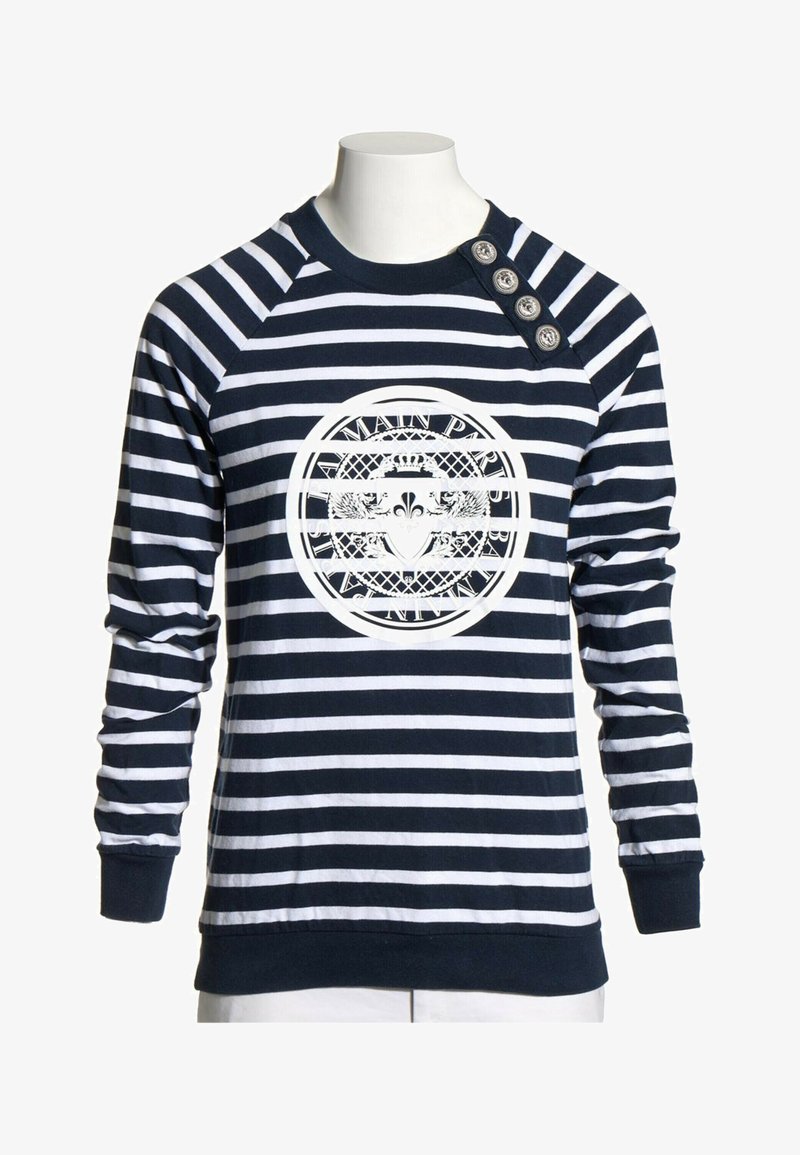 Chemise à manches longues rayée bleu marine et blanc avec quatre boutons décoratifs sur l'épaule et un emblème circulaire avec texte et blason sur la poitrine.