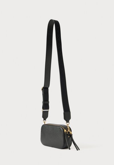 Pequena mala de couro preta de ombro com fechos dourados e uma alça ajustável larga, apresentando padrões circulares em relevo.