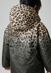 Leopardenmuster Pufferjacke mit Kapuze. Aus glänzendem Stoff, mit kontrastierenden beigen Flecken und großen schwarzen Buchstaben auf dem Rücken.