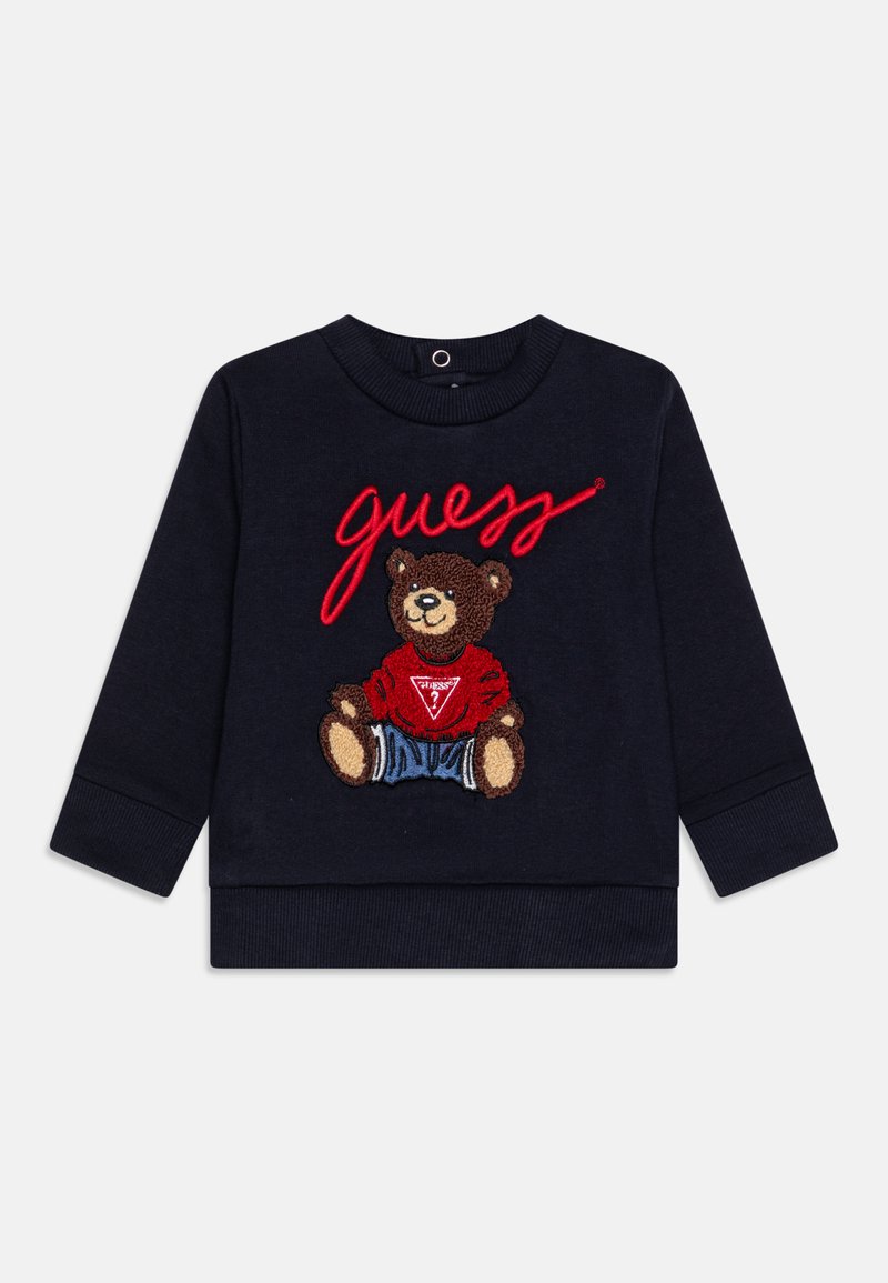 Felpa blu navy con ricamo di un orso che indossa una maglietta rossa e pantaloni corti in denim, con la scritta "guess" in rosso sulla parte anteriore.