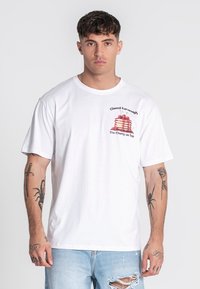 Camiseta de algodón blanca con un gráfico de pilas de pancakes con cerezas rojas. Corte holgado, con mangas cortas y escote redondo.