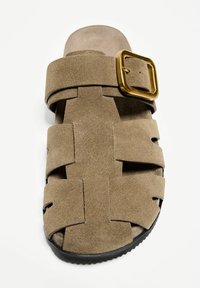 Rjavi semiš copat s širokim križnim trakom, nastavljivo zlatno sponko in strjeno črno podplato.