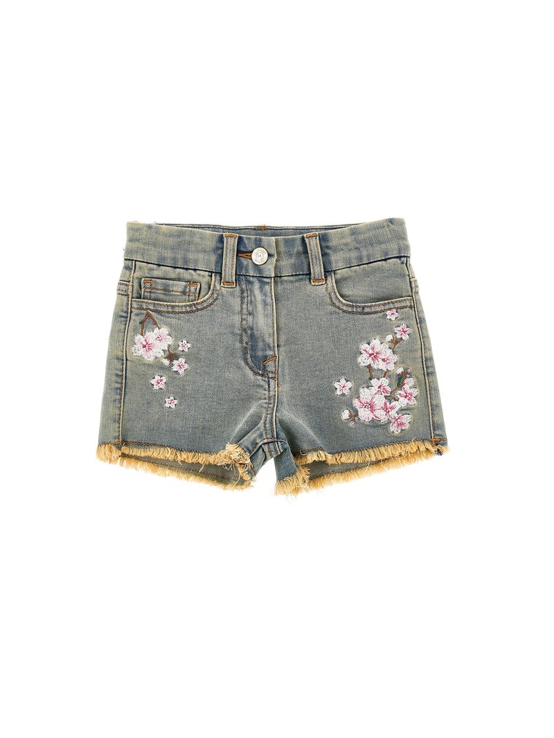 Shorts de mezclilla con dobladillo deshilachado, lavado azul claro, que presentan bordados florales en rosa y blanco en ambos lados frontales. Cierre de botón, costuras cosidas.