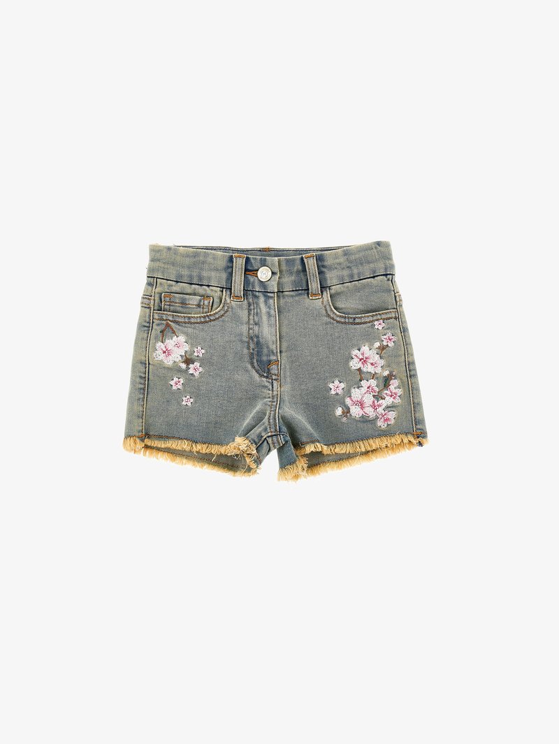 Jeansshorts med fransad nederkant, ljusblå tvätt, med blommig broderi i rosa och vitt på båda framsidorna. Knapplåsing, sydda sömmar.