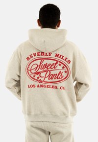Sudadera color crema con un diseño gráfico rojo en la parte trasera, que presenta "Beverly Hills Sweet Pants Los Ángeles, CA" y estrellas.