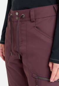 Bordeauxrode broek met een gestructureerde afwerking, voorzien van een ritszak, een verstelbare trekkoord taille en contrasterende stikseldetails.