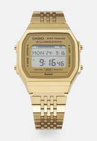 Montre numérique en or avec un cadran rectangulaire, fonction de suivi des pas, résistance à l'eau et bracelet en maillons métalliques. Affiche l'heure et la date.