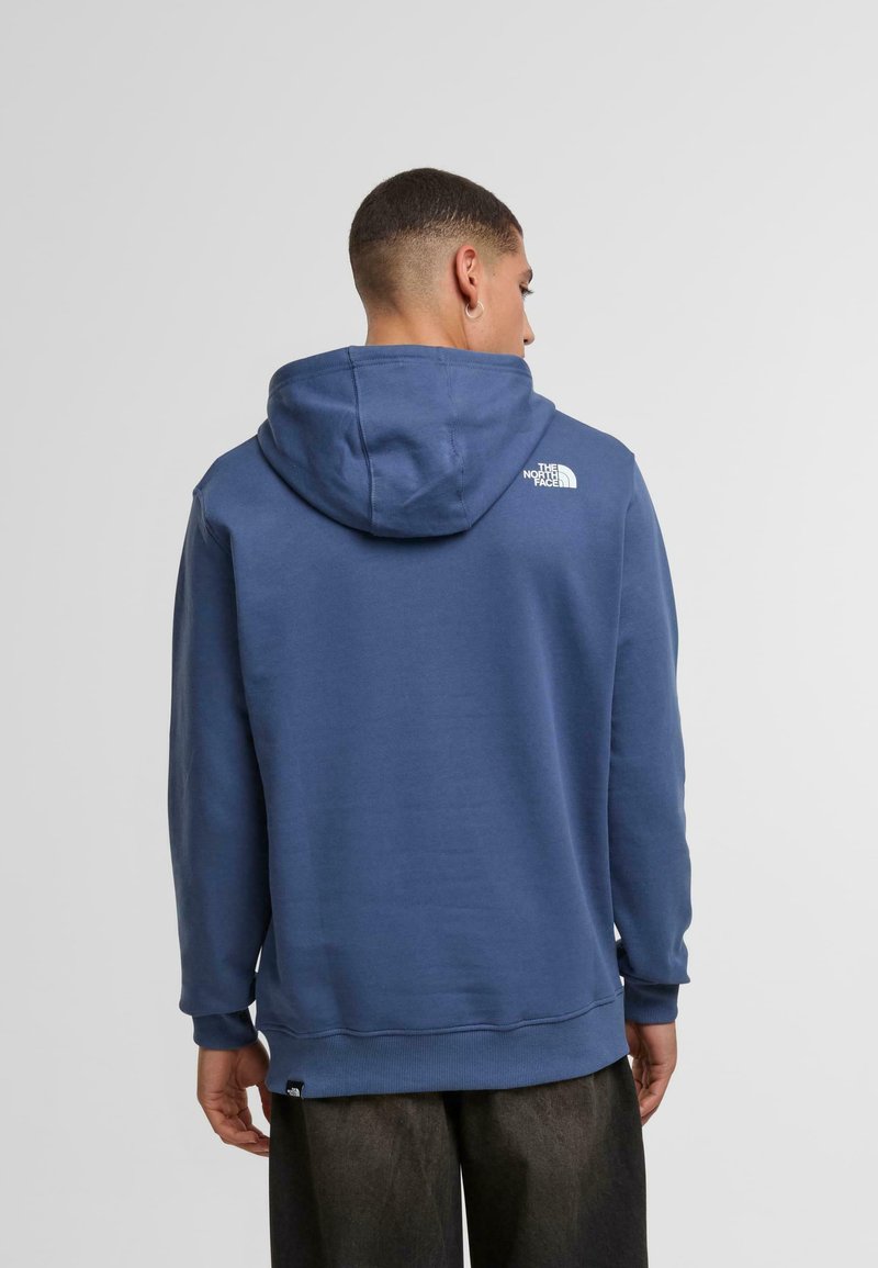 Hoodie in diepblauwe stof, met een wit logo op de achterkant, ribbelboorden en -zoom voor extra textuur en pasvorm.