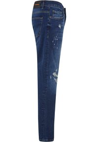 Jeans de denim azul con corte slim, que presentan detalles desgastados y decoloración en la parte frontal. Tienen bolsillos estándar y una etiqueta de cuero en la cintura.