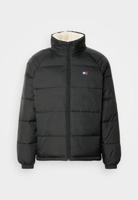 Doudoune noire avec col haut, dotée d'une fermeture éclair à l'avant et de poignets élastiques. L'intérieur est doublé d'un tissu crème doux.