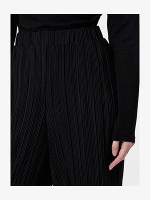 Čierne plisované nohavice s textúrovanou tkaninou a širokým elastickým pásom. Viditeľné vertikálne plisovanie pridáva hĺbku a detail.