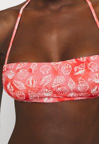 Top de biquíni cor-de-rosa com padrão de conchas brancas, tecido liso e elástico, alças halter, design com faixa, adequado para trajes de banho.