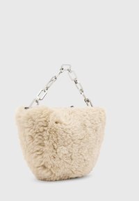 Kabelka z umelého kožušiny v krémovej farbe s textúrovaným, nadýchaným povrchom a strieborným reťazovým remienkom. Zaoblený tvar, horné zapínanie na zips.