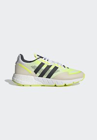Adidas apavi balta, neona dzeltenā un melnā krāsā. Acs augšdaļa ar trim melnām svītrām. Teksturēta zole un mīkstināta apkakle atbalstam.