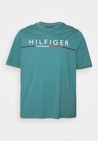 Tyrkysové bavlněné tričko s krátkým rukávem, kulatým výstřihem a bílým logem "HILFIGER" přes hruď, doplněné červenými a námořnickými pruhy.