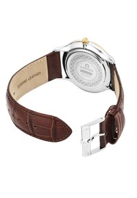 Cinturino in vera pelle marrone con cassa in acciaio inox argentato lucido, corona dorata e fondo orologio dettagliato e texture.