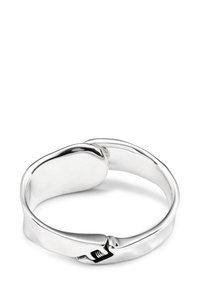 Anello in metallo argentato con una finitura liscia e lucida. Presenta un design con chiusura regolabile e una forma rotonda e fluida.