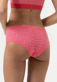 Rosa spetsunderkläder med en scalloped kant, blommönster och en elastisk midja. Designen betonar komfort och passform.