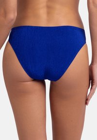 Modri bikini del, teksturirana tkanina z gladkim zaključkom, zmerna pokritost in brezšivne robove, ki poudarjajo preprost, klasičen dizajn.